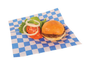 Hamburger, sliced tomatoes, onions, and lettuce placed on blue checkered wax paper