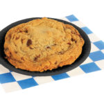 Chocolate chip cookie with pecans n a small black plate