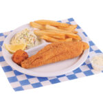 1pc. fried catfish plate served with french fries, coleslaw, a slice of garlic bread, a hush puppy, and a lemon wedge served on a white plate. Placed in a white and blue checkered paper.