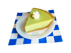 slice of key lime pie with whip cream on a white plate on a blue and white checker paper