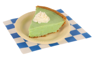 Slice of Key Lime pie with a dollop of whipped cream. On a small beige plate placed on a white and blue checkered paper
