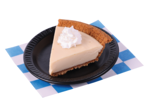 Slice of Key Lime pie with a dollop of whipped cream. On a small black plate placed on a white and blue checkered paper