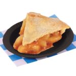 Apple pie slice on a black plate. Placed on a blue and white checkered paper.