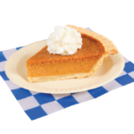 Slice of pumpkin pie with whip cream plated on a white and blue checker paper