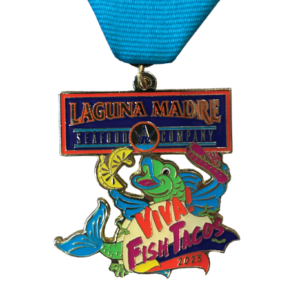 Laguna Madre Seafood Company 2023 fiesta medal with a green and light blue fish holding a sombrero inside a tortilla with two lemon slices. Verbiage "Viva! Fish Tacos 2023" 
