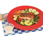Garden Salad with Salmon served carrots, cucumbers, tomatoes, two slices of avocado, and ranch dressing.