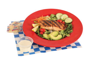 Garden Salad with Salmon served carrots, cucumbers, tomatoes, two slices of avocado, and ranch dressing.