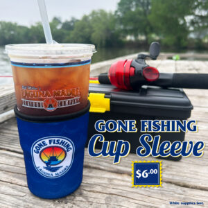 Gone Fishing Cup Sleeve. $6.00 price sticker. While supplies last. The image features our new Laguna Madre cup sleeve on a fishing dock with a tackle box and fishing rod in the back of the tea with a lake view background.