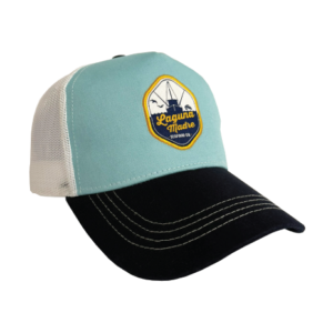 The image features a trucker-style hat with a light blue front panel, white mesh back, and a black curved brim with white stitching. A yellow-and-blue patch on the front displays the Laguna Madre logo.